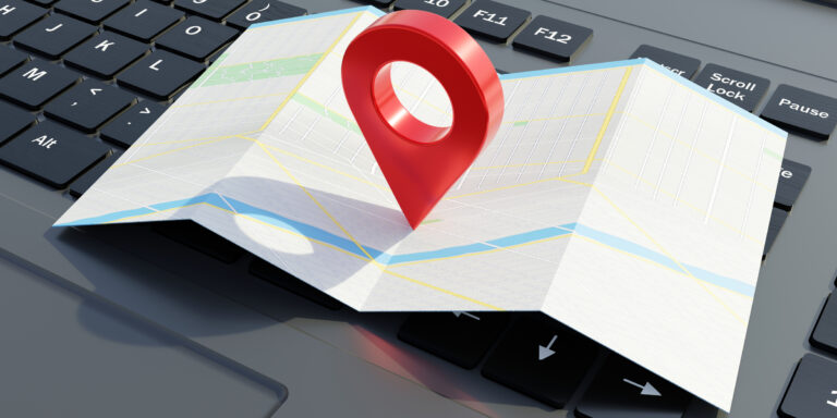 GPS navigation pointer on a map, laptop computer background. City map application.